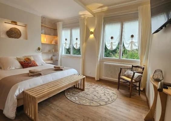 Chambre lumineuse du Gite du chasselas à Prayssas — lit double et fenêtres habillées de rideaux clairs