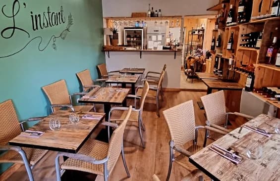 Intérieur de l'épicerie fine L'Instant — salle avec tables et écriture peinte au mur