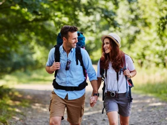 Couple de randonneurs avec sacs à dos sur un chemin boisé des coteaux de Prayssas