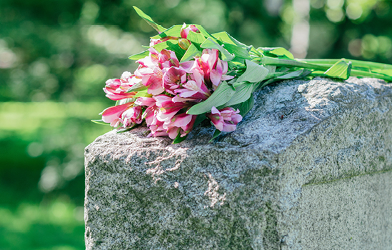 Bouquet de fleur rose sur une pierre tombale dans un cimetière