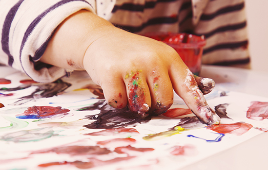 Gros plan sur la main d’un enfant peignant avec ses doigts